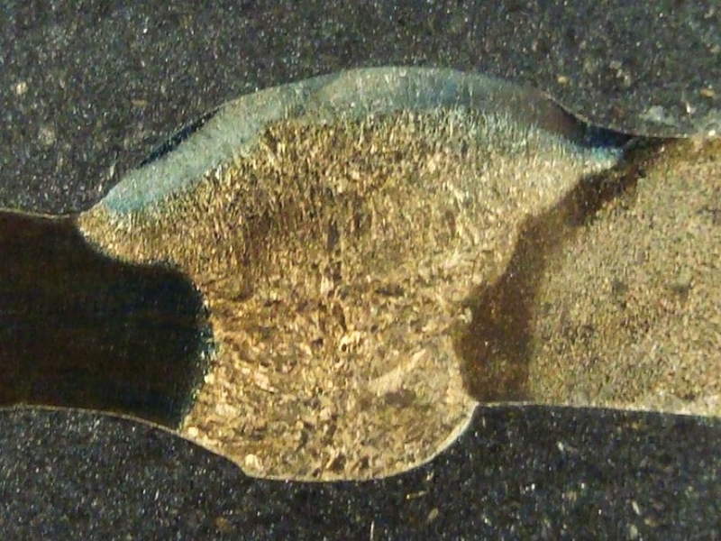 Macrography of a longitudinal section of the flange to pipe weld, cracked in the flange. Pipe thickness, measured, is 5 mm. Flange thickness at the welded region is 7.5 mm. The macro was etched using NaOH solution, electrolytic.