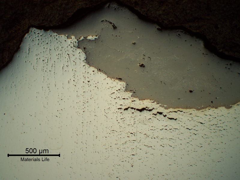 Micrography of a longitudinal section of the bolt at the fracture surface. The material showed several creep voids and interconnected cracks. The broken bolt remained in service during some time and the fracture surface presented a thick oxide layer(grey). As polished.