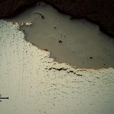 Micrography of a longitudinal section of the bolt at the fracture surface. The material showed several creep voids and interconnected cracks. The broken bolt remained in service during some time and the fracture surface presented a thick oxide layer(grey). As polished.