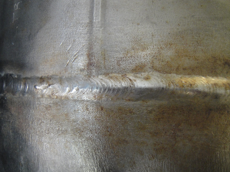External aspect of the 8" diameter pipe that suffered localized thinning and leakage associated to the welded regions. The vertical weld is the pipe seam and the horizontal weld is the circunferential butt weld.