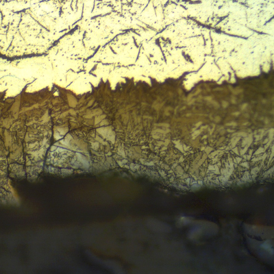The pipe base metal, at the internal surface, presents a hydride layer showing that the environment is absorbing hydrogen.  Although there are microcracks in this layer it did not detach in the base metal.