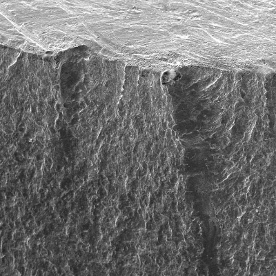 The fracture surface of the main pipe is presented in low magnification (external pipe surface in the top) showing a flat propagation starting from the contour of the weld margin.