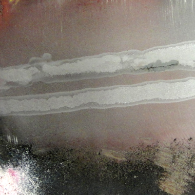 The internal surface of the 2 1/2" thickness plate drum was welded to attach a baffle plate (1/4" thick) using two fillets (one in each side of the plate to shell), but the welding procedure was not suitable since cracks appeared underbead, although they were detected only after 6 month in operation, when the baffle was removed. The picture shows a macrography of the surface, with the cracking.
