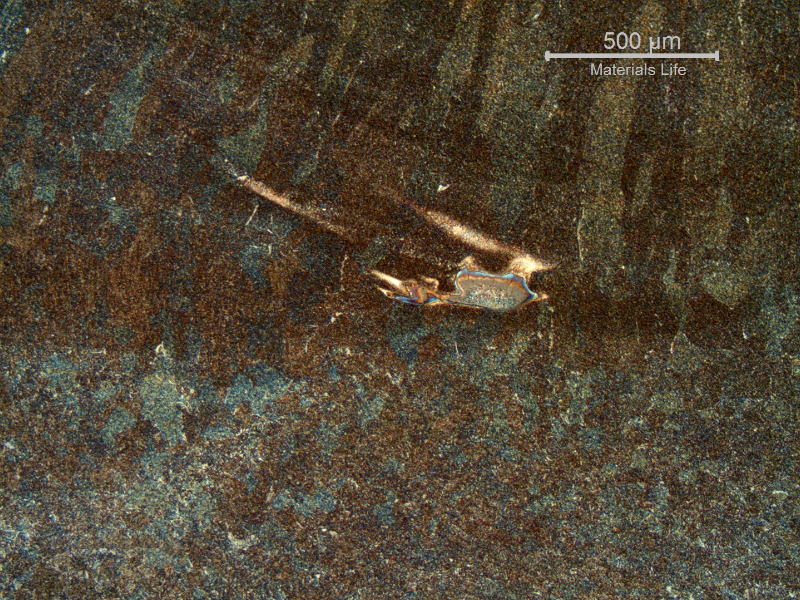 Low magnification micrography of the weld metal, evidencing regions of low dilution of the entrapped carbon from the arc gouging.
