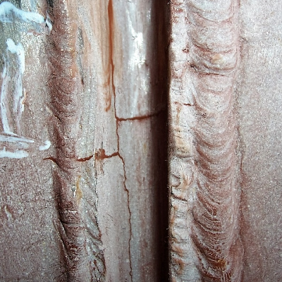 After grinding to remove the cracks, it was possible to see that they originated in the root, with longitudinal and transverse cracking, and localized in the weld metal only.