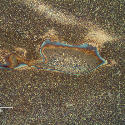 Detail of a region of entrapped carbon from the arc gouging, in the weld metal.