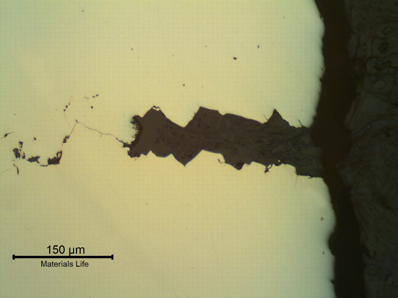 Transverse section of the fitting that suffered a longitudinal cracking. As polished. The wrought fitting has suffered intergranular stress corrosion cracking from the internal surface, exposed to hot caustic environment.