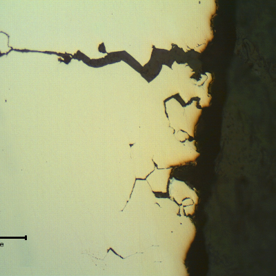 Transverse section of the fitting that suffered a longitudinal cracking. As polished. The wrought fitting has suffered intergranular stress corrosion cracking from the internal surface, exposed to hot caustic environment.