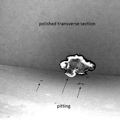 Aspect of a micrographic sample by scanning electron microscopy showing the external pipe surface, in the bottom, the fracture at the left side of the figure and several spots of pitting corrosion from the external surface.  The polished section (transverse to the fracture and in a longitudinal section of the pipe) shows the morphology of the pit , 0.2 mm depth. Original magnification 50x.