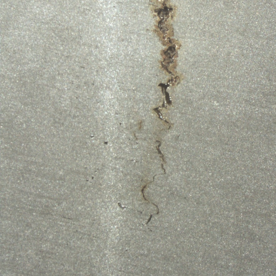 Longitudinal section of the mooring chain at the welded region in a position where the crack did not propagate to the surface yet. It is possible to see the crack parallel to the butt weld and presenting an irregular shape.