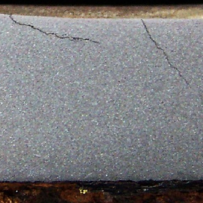 Macrography of a transverse section of the steam drum sample that was removed after the inspection had detected multiple cracks propagating into the thickness, more than 50% deep in the thickness.