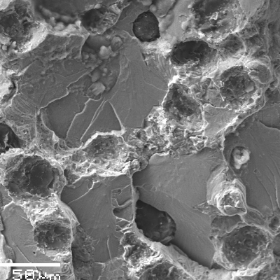 The fracture surface is flat, shows the graphite nodules and cleavage of the ferritic microstructure, indicating that the material have exceeded the capacity to acomodate the stress.