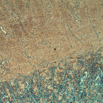 Micrography of the weld metal (cap) at the surface.  It is clear that the last bead of the weld was remelted in an autogenous condition, probably to create a better finish, since the layer is less than 2 mm deep. This is a typical bad practice since a large amount of ferrite is retained by the quick cooling.