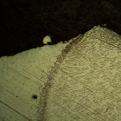 The micrography of the welded joint between the flange and the shell, in a region that was through wall cracked, the fracture propagating in the shell plate base metal.