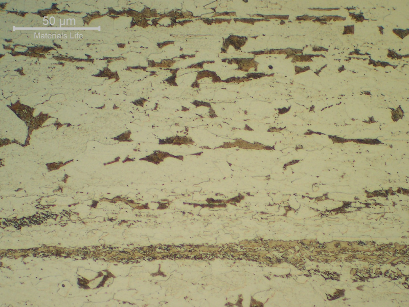 Detail of the microstructure in the center of the plate, in the longitudinal section.  The ferritic structure is refined and presents different grain sizes. Carbides are presented in different morphologies (perlite, precipitated) and there are probably microphases (aligned in a central segregation line).
