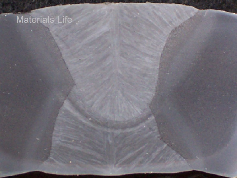 Macrosection transverse to the longitudinal seam weld, presenting the two passes, the first welded from the internal side and the second welded from the external side. It is possible to see the columnar grains of the weld and the heat affected zone (HAZ) from each pass. See the schematic drawing in the next figure