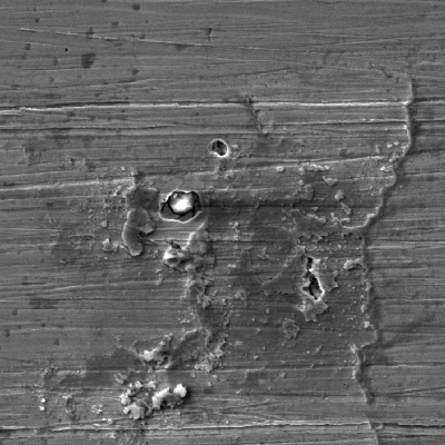 Aspect of the rusted surface after cleaning, showing adhered products at the surface, in regions where the passive layer was destroyed and pitting corrosion occurred.