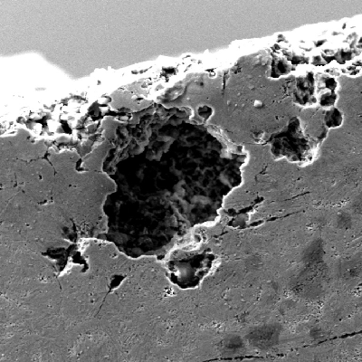 Micrographic aspect of the pitting corrosion at the knife surface.  It is possible to see the typical pitting aspect of a localized corrosion that appears as a small dot at the surface but it is a big crater under the surface.