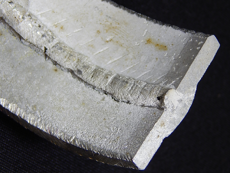 Internal surface detail of the 3 1/2" pipe, cut in a longitudinal section (transverse to the weld), presenting a localized corrosion at the margin of the welded joint (Keller etched), in the root.  The pipeline was assembled with pipes manufactured in two different aluminum alloys, AA 3003 (top of the figure) and AA 6063 (bottom of the figure), and the localized corrosion occurred at the fusion line of the 6063 pipe.