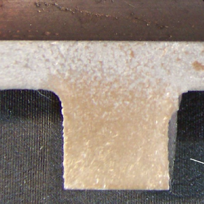The macrography of a longitudinal section of the camshaft (tubular) in a position where there are two chilled lobes, presenting a strong microstructural change through thickness, from the hard chilled surface (500HV10) to the soft region in the middle of the thickness (187HV10).