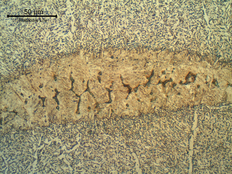 Micrography of the weld metal presenting a martensitic island with microcracks, due to a localized increase in the manganese and silicon content, probably because an active flux was adopted in a condition where a high cleanning action was not required. A high flux-to-wire ratio (>1) could also be an issue.