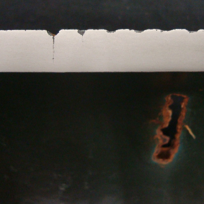 The longitudinal section of the 1/2" thick pipe close to the washout position shows that the external tool marks are like notches that are corroded and cracks are iniciating from the corroded regions.  The top of the figure presents the external pipe surface and the bottom of the figure presents the internal pipe surface, with a green coating and the rusted washout.