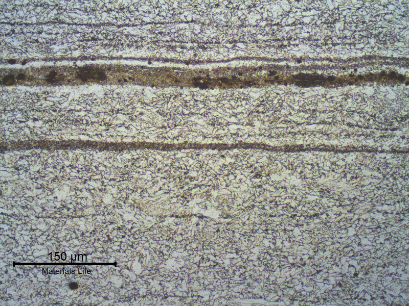 Micrographic detail of the X65 pipe, 5/8" thickness, in the longitudinal section.In the center of the pipe thickness there is a segregation band of bainitic structure. The cracking was not associated to the pipe but to the other side, the forged connector.