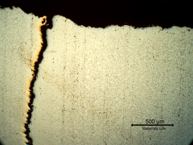 Micrography of a longitudinal section of the stud, at the fracture surface in the center of the thickness, showing a long secondary cracking (vertical in the left).