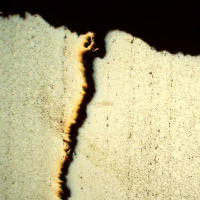 Micrography of a longitudinal section of the stud, at the fracture surface in the center of the thickness, showing a long secondary cracking (vertical in the left).
