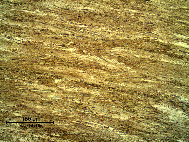 The longitudinal section of the spring wire shows a strain hardened martensitic structure, aged to high strength (602 HV 0.3kg). Previous austenite grains are elongated.