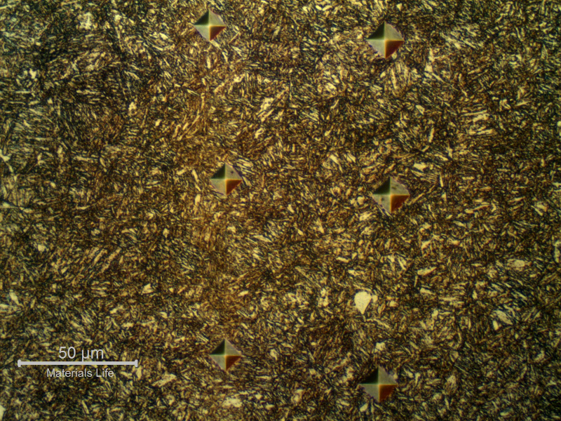 Micrographic detail of the banded region, with microhardness identations indicating that the longitudinal bands are harder than the rest of the structure. The measurements in the band are 466, 447 and 460 HV50g; and out of the band are 358, 360 and 362 HV50g, from the top to the bottom.