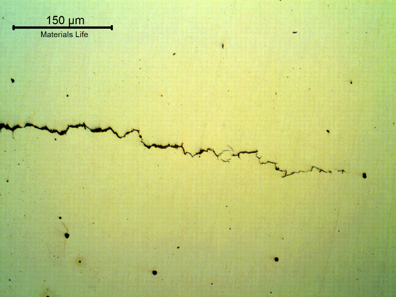 Micrography of a longitudinal section of the bolt, as polished, presenting brittle cracks, transverse to the bolt axis.