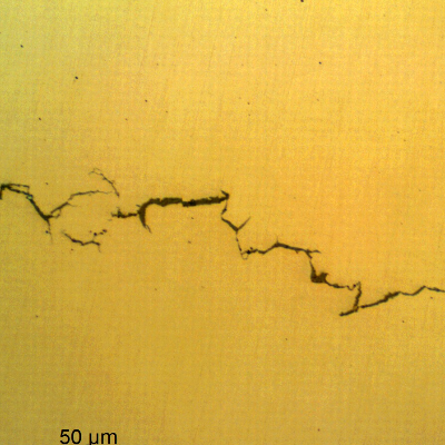 Micrography of a longitudinal section of the bolt, as polished, presenting brittle Intergranular and transgranular cracks, transverse to the bolt axis.