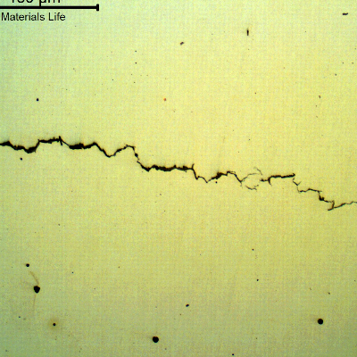 Micrography of a longitudinal section of the bolt, as polished, presenting brittle cracks, transverse to the bolt axis.