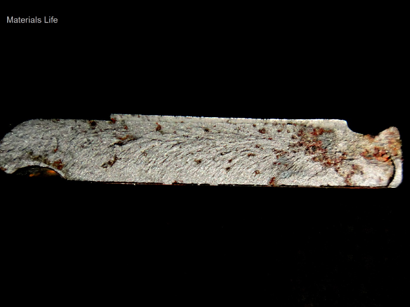 Macroscopic aspect of the fracture surface, showing a brittle behavior (chevron marks) and a starting point at the bottom of the groove in the right side of the figure.