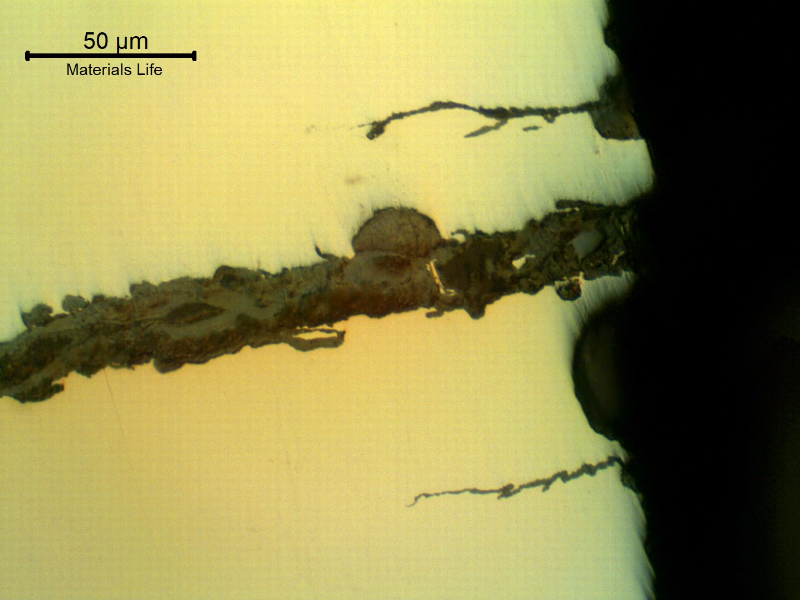 As polished micrography of the external surface of the tubular equipment, close to the fracture position (it is to the top of the figure), showing corrosion fatigue cracks. These are multiple cracks, paralel to the main fracture, slightly branched and fully filled with oxides.