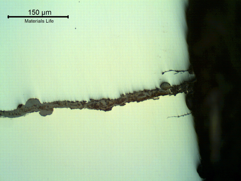 As polished micrography of the external surface of the tubular equipment, close to the fracture position (it is to the top of the figure),  showing corrosion fatigue cracks.  These are multiple cracks, paralel to the main fracture, slightly branched and fully filled with oxides.