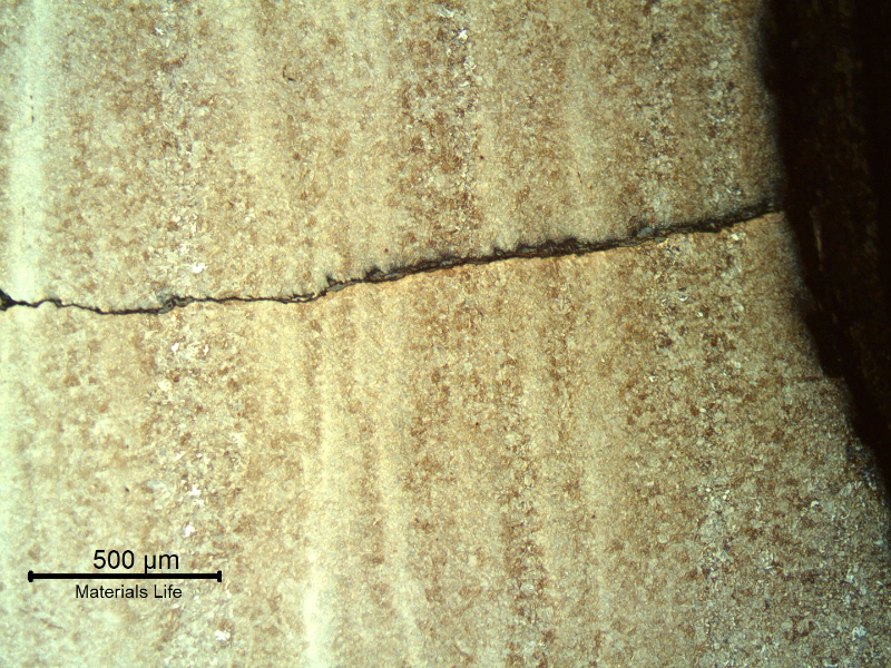 Micrography of a longitudinal section of the tubular tool, at the external surface close to the fracture position (it is to the top of the figure), showing multiple cracks, slightly branched, fully filled with corrosion products, typical of a corrosion fatigue mechanism.  It propagates in a straight front, not affected by banded structures,