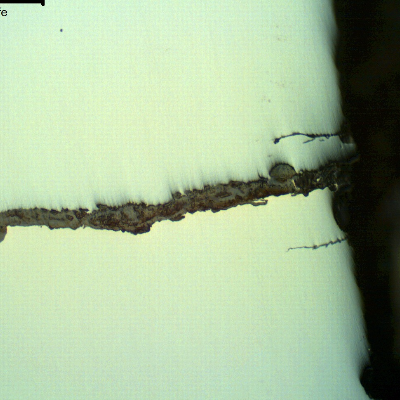 As polished micrography of the external surface of the tubular equipment, close to the fracture position (it is to the top of the figure),  showing corrosion fatigue cracks.  These are multiple cracks, paralel to the main fracture, slightly branched and fully filled with oxides.