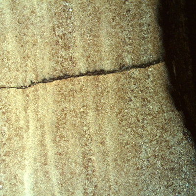 Micrography of a longitudinal section of the tubular tool, at the external surface close to the fracture position (it is to the top of the figure), showing multiple cracks, slightly branched, fully filled with corrosion products, typical of a corrosion fatigue mechanism.  It propagates in a straight front, not affected by banded structures,