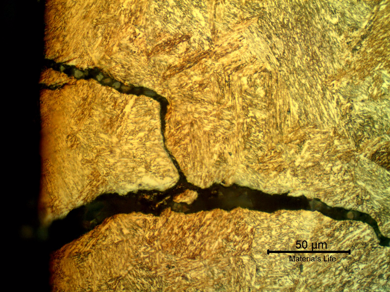 Micrography of the pin in a longitudinal section, at the pin surface showing a secondary crack, without plastic deformation, filled with products and branched.