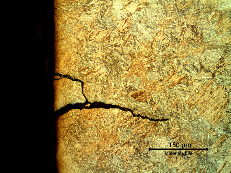 Micrography of the pin in a longitudinal section, at the pin surface showing several secondary cracks, without plastic deformation, filled with products and branched.