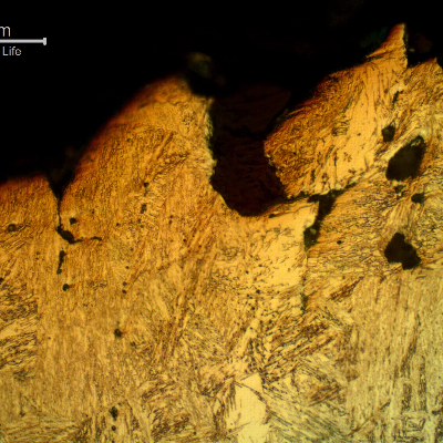 Micrographic detail of the pin in a longitudinal section, transverse to the fracture surface, at the ductile final fracture, presenting microvoids connecting with plastic deformation of the structure.