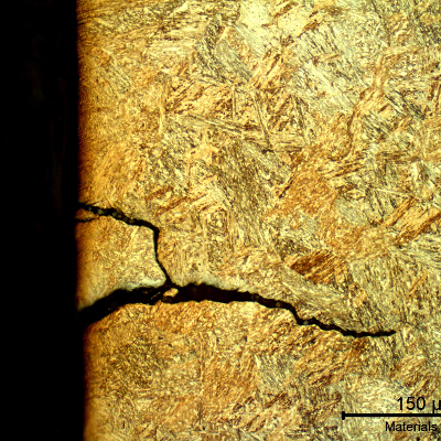 Micrography of the pin in a longitudinal section, at the pin surface showing several secondary cracks, without plastic deformation, filled with products and branched.