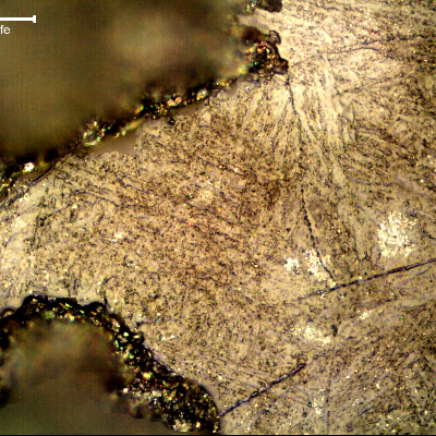 The micrographic aspect of the corroded surface, after polishing and etching with Kalling, shows the margin of one pit and microcracks propagating through previous austenite grain boundaries of the martensitic structure, probably associated to the biological attack and material embrittlement. Replication technique.