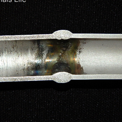 Macrography of the fitting to tubing welded joint. The internal surface of the fitting (left side) is rough compared to the internal surface of the tubing (right side). The cracking is located only in the fitting and presented no association with the welded joint.