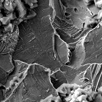 The through wall cracking was opened by citting the two sides and the aspect was characterized by SEM.  Although there was a film at the fracture surface, probably because the fitting was removed from service some time after it was leaking, the fracture micromechanism is by quasecleavage, typical of a stress corrosion cracking.