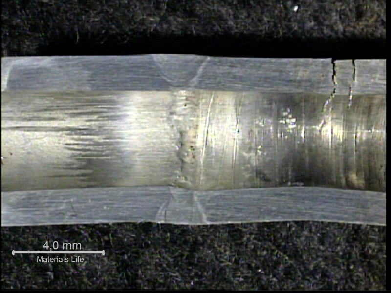 The longitudinal section macrography of the welded joint sample shows that the cracks are positioned in the fitting, about 10 mm far from the weld.