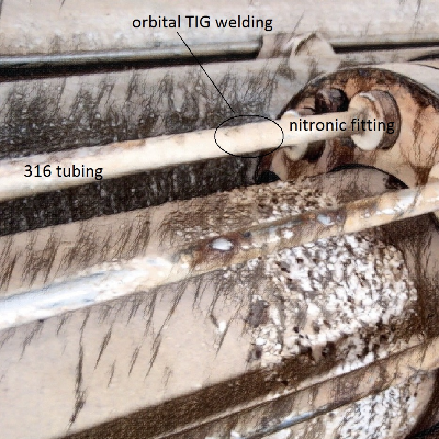 Draft of the completion riser after removal of the external case showing the hydraulic line position where the 316 tubing is welded by orbital autogenous GTAW to the Nitronic fitting (stab). In the design of these hydraulic lines, the position of the cracking in the fitting is associated to a slightly bent condition of the fitting due to the misaligment of the tubing axis and the stab axis in the connector, visible in the draft.