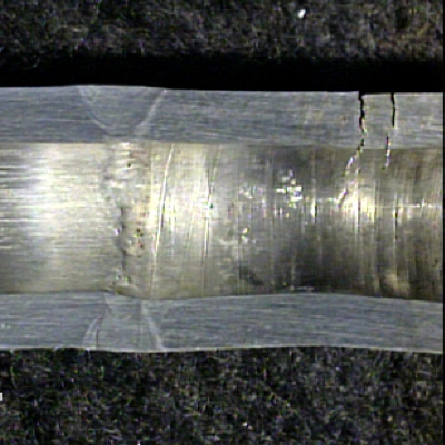 The longitudinal section macrography of the welded joint sample shows that the cracks are positioned in the fitting, about 10 mm far from the weld.